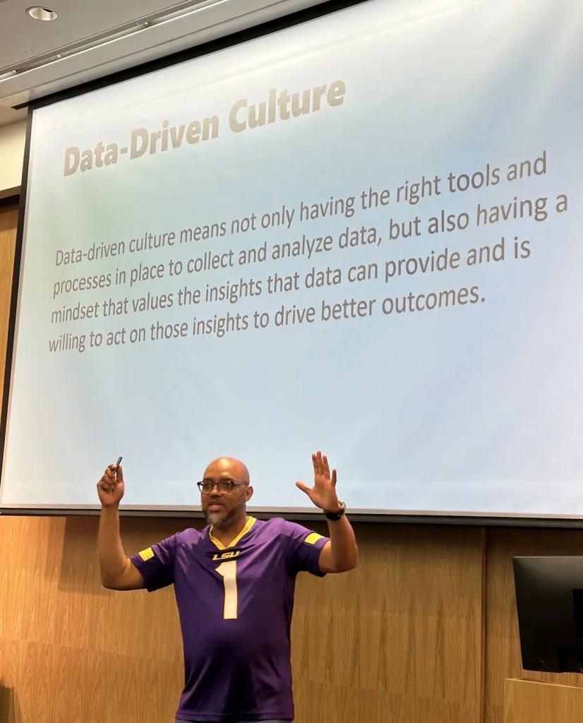 Patrick LeBlanc wearing a LSU purple shirt in front of a slide titled Data-Driven Culture