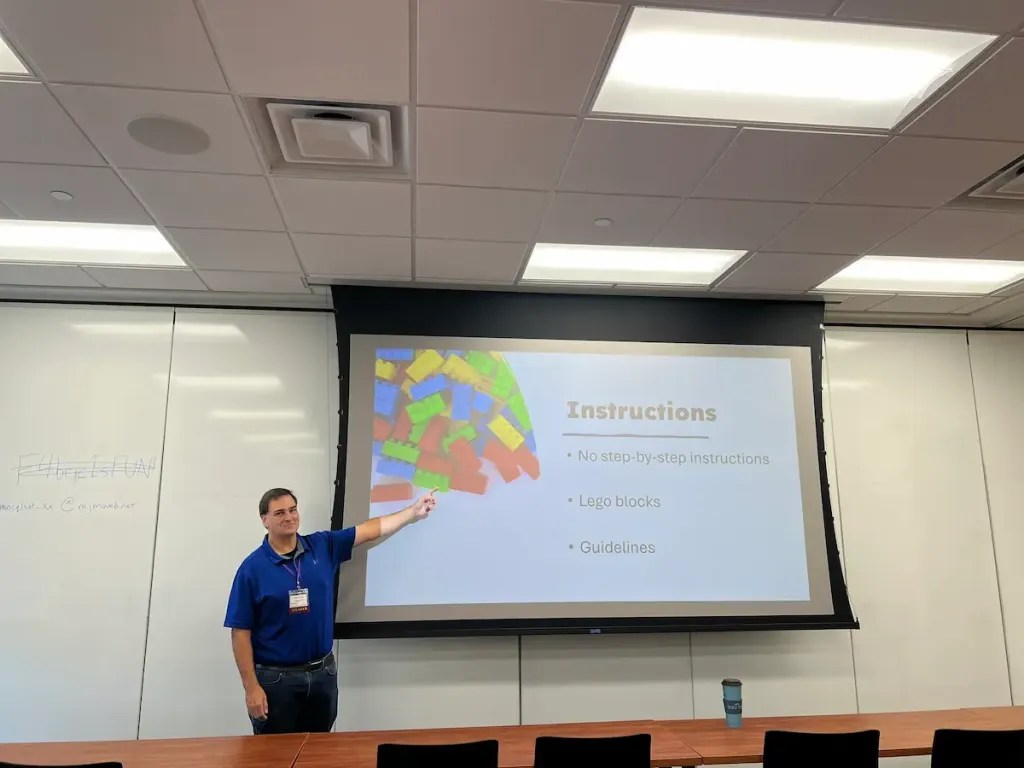Jason Romans presenting a slide showing Lego blocks and the words Instructions - No step-by-step instructions, Lego Blocks, Guidelines