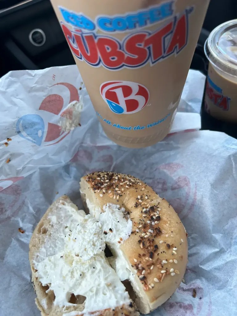 Everything bagel with cream cheese and an ice coffee in a cup labeled Cubsta from Brooklyn Water Bagel