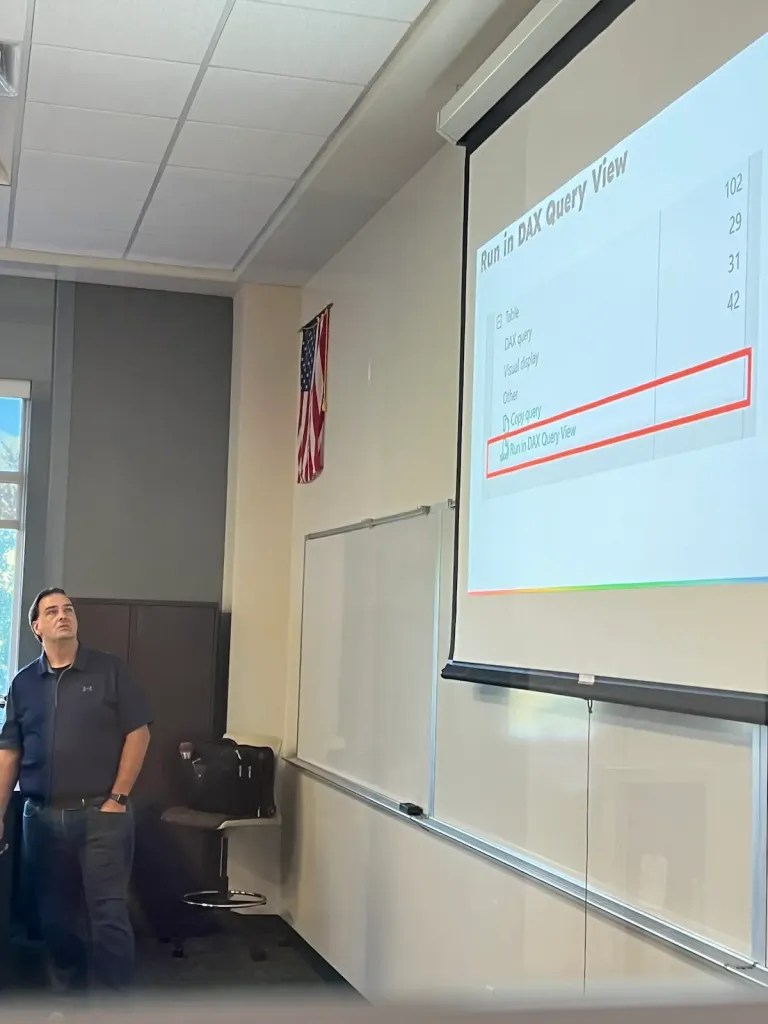Jason Romans presenting with a slide showing of DAX Query View