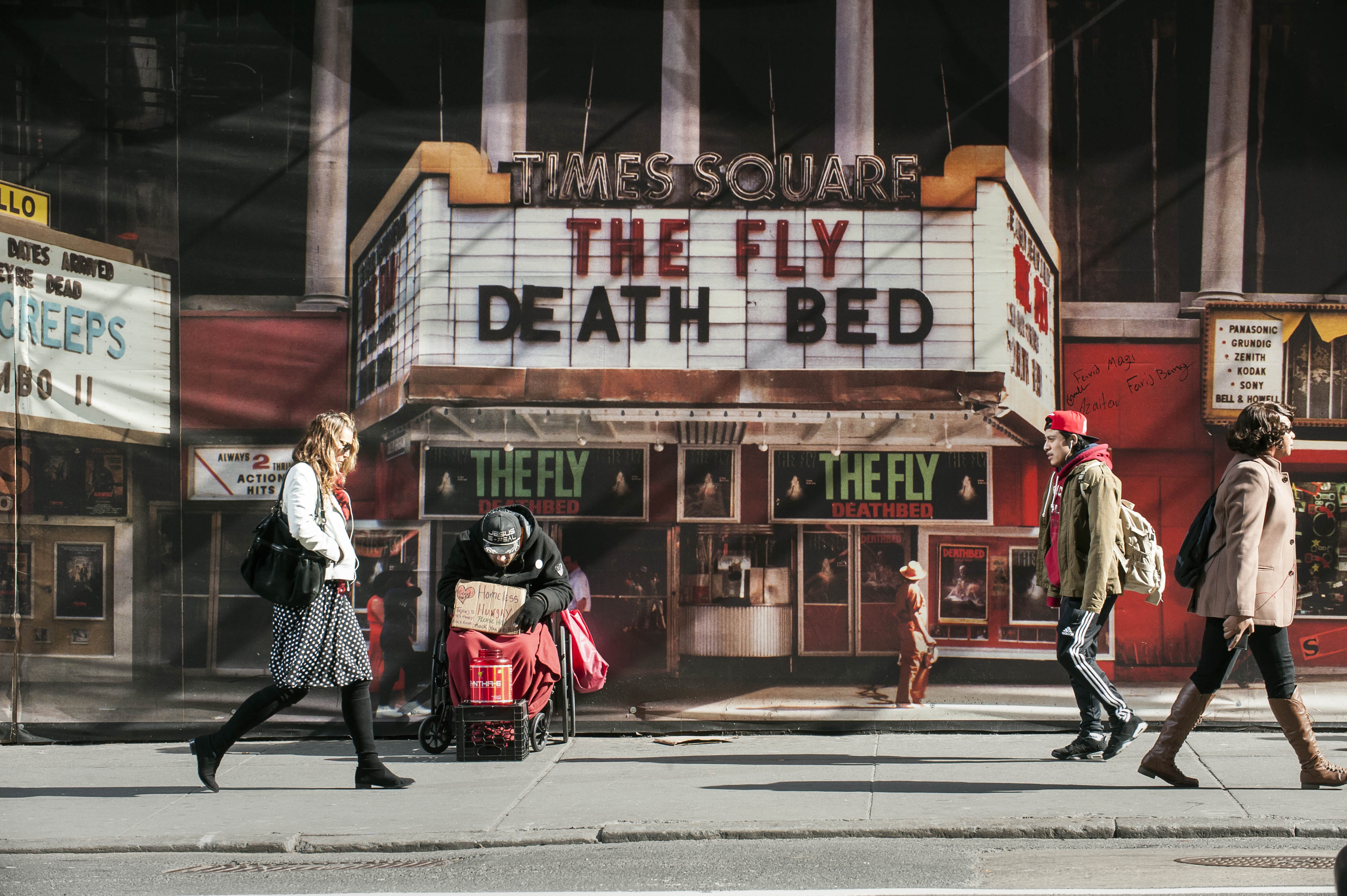 Panhandler in front of photographic mural depicting Times Square circa 1987, West 42nd Street between 7th and 8th Aves, NYC.
