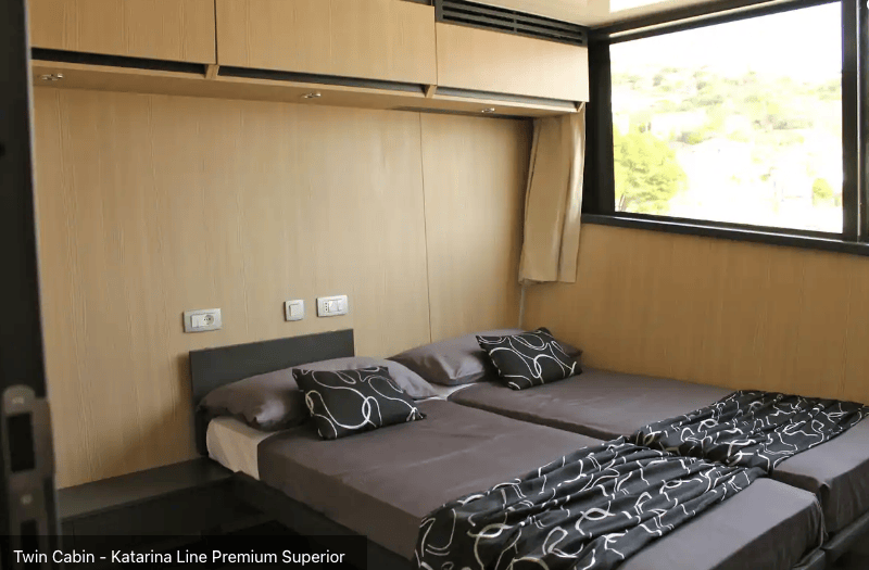 Twin beds beside large window and storage