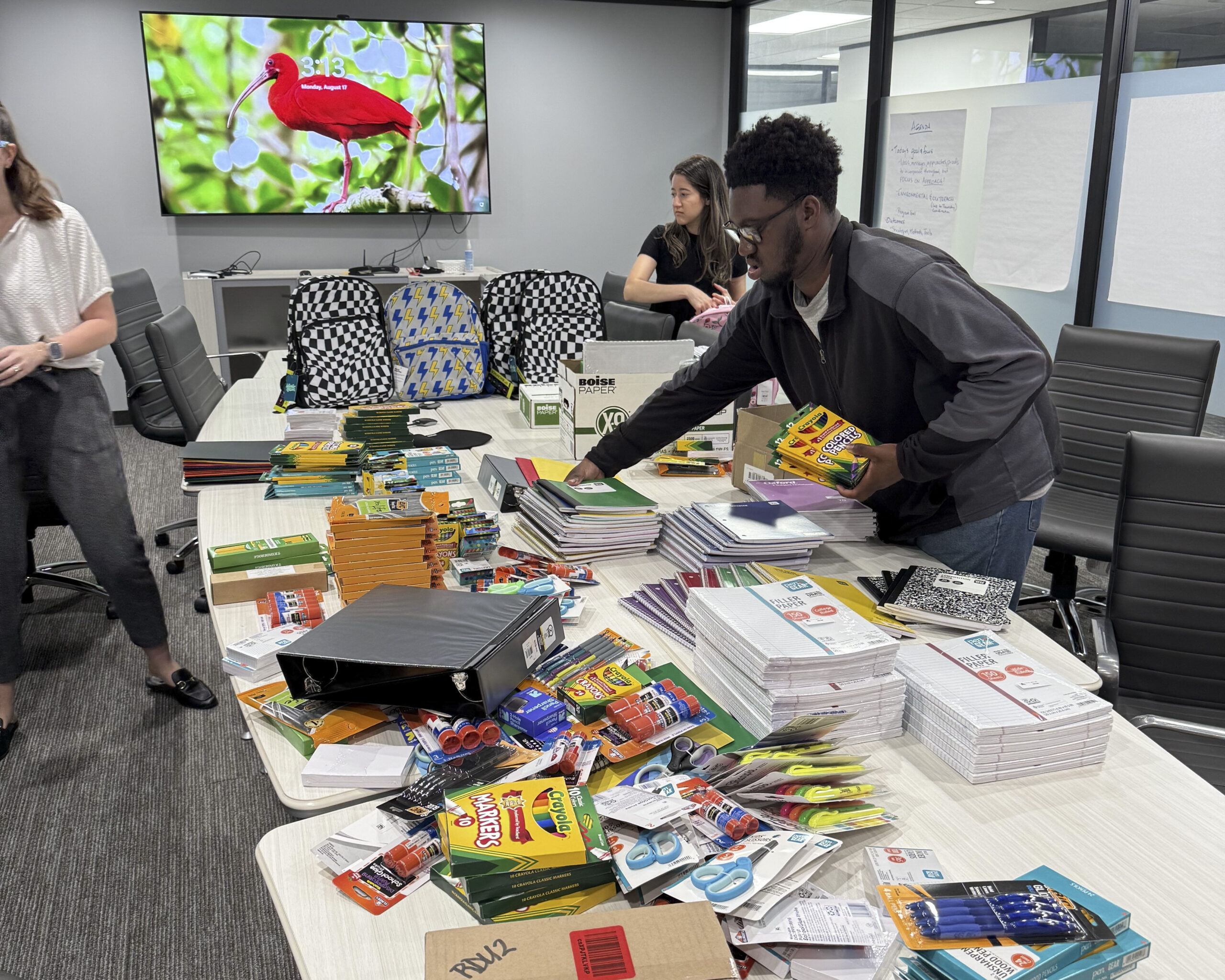 DCCM team members organizing donated school supplies on a conference room table.