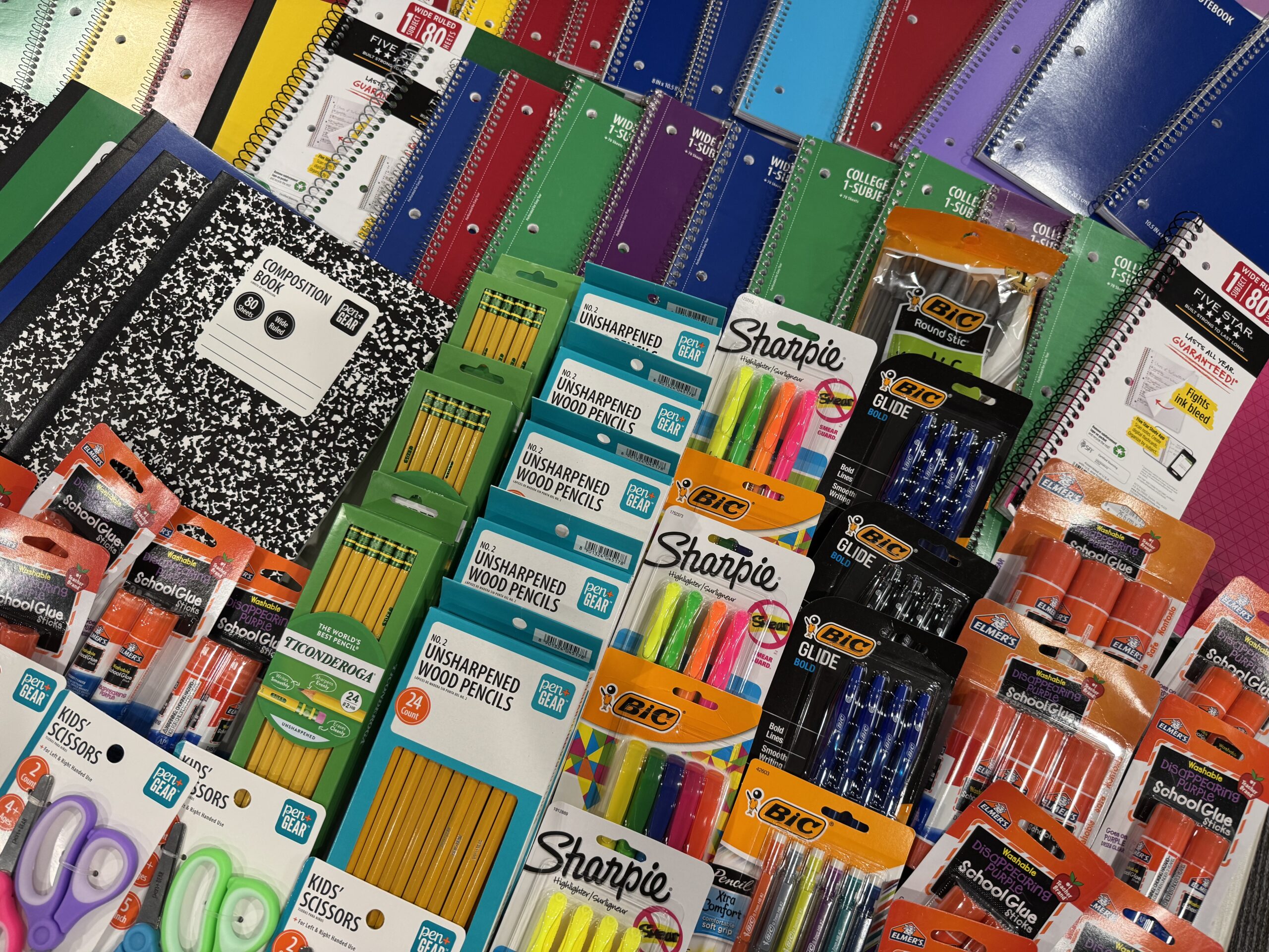 Close-up of donated notebooks, pencils, highlighters, pens, glue sticks, and scissors.