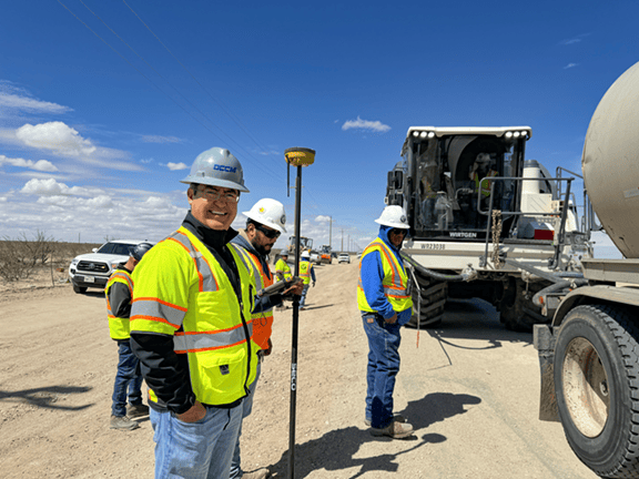 Transportation construction manager standing at an active bridge and roadway construction site with excavation and structural work underway.