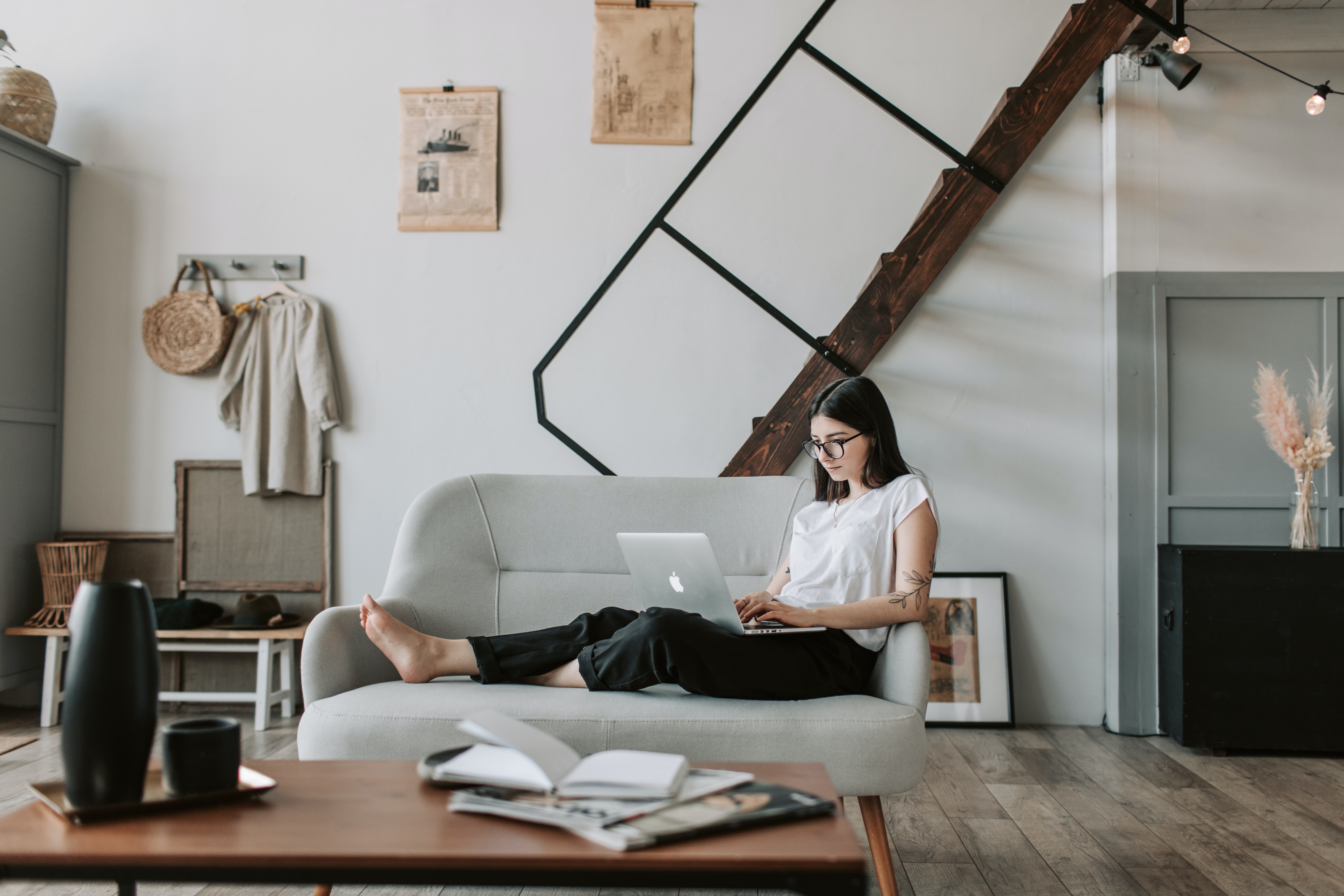 A woman sitting on sofa in a modern, simple apartment, typing on her laptop, to introduce the top of writing business emails