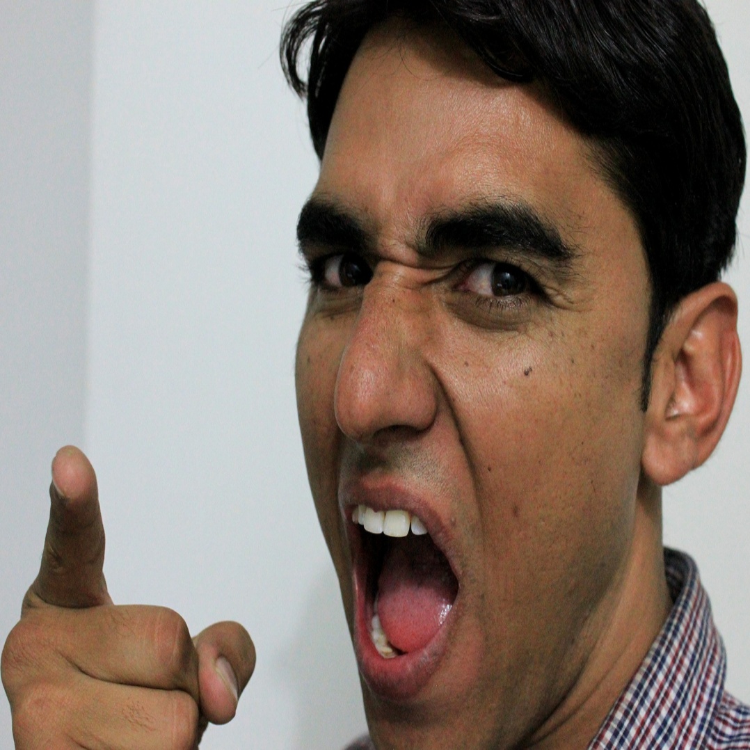 A picture of an angry man shouting and pointing at the camera.