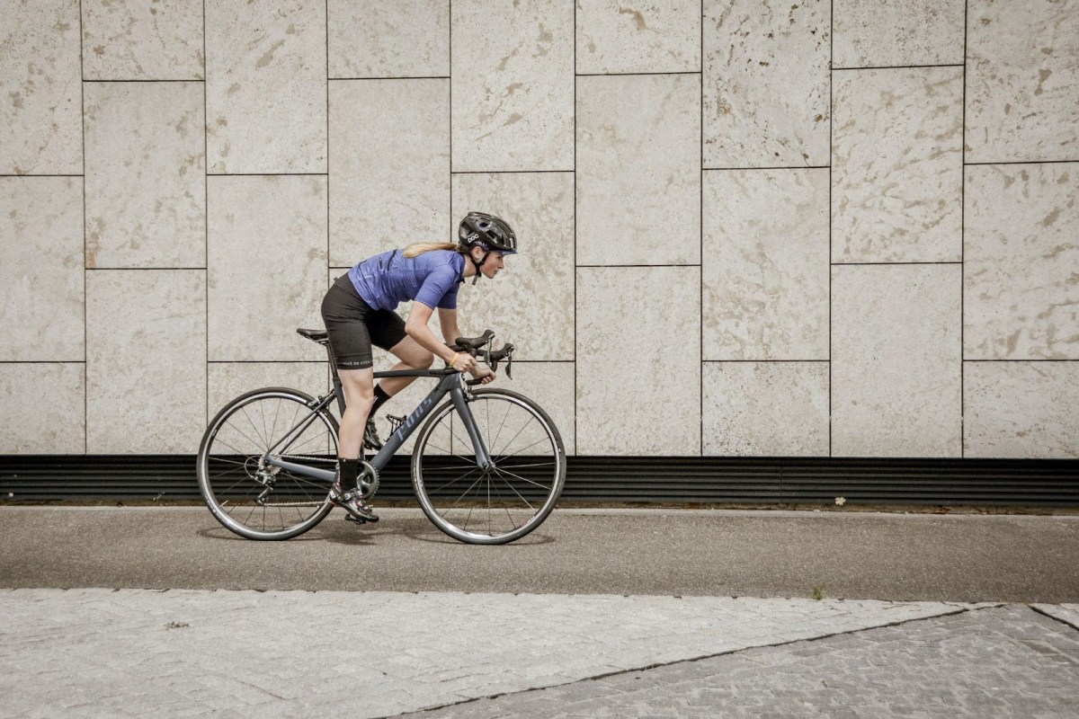 A picture of a woman riding a road bike in an urban setting.