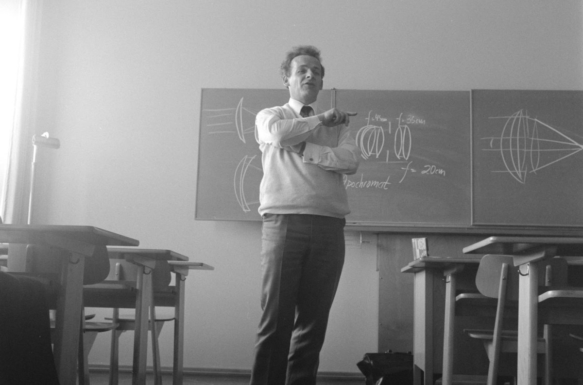A black and white picture of an older male teacher lecturing to a class.