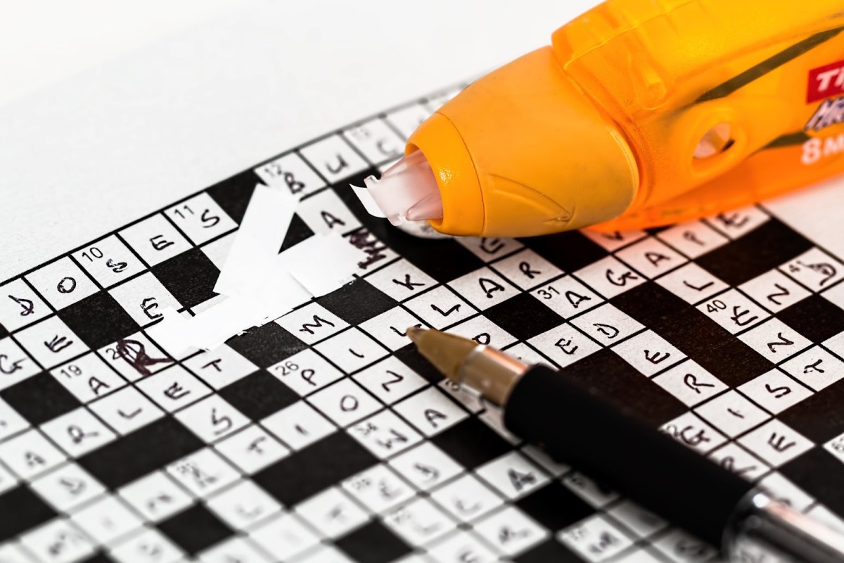 A close up of a crossword puzzle that has had an error fixed with correction tape, symbolizing holding non-native speakers to a higher standard.