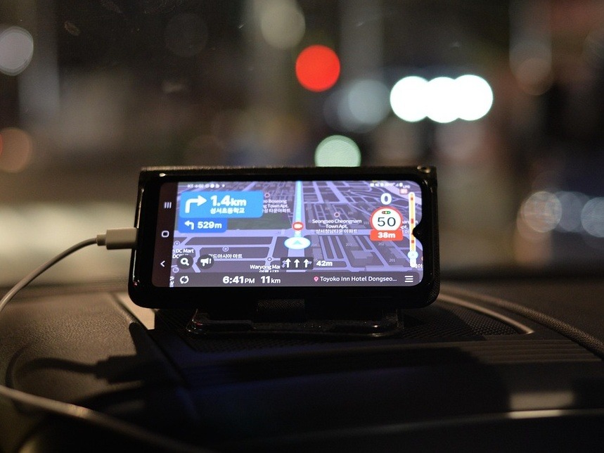 Smart phone on a car dash displaying the Naver Maps app, showing street directions