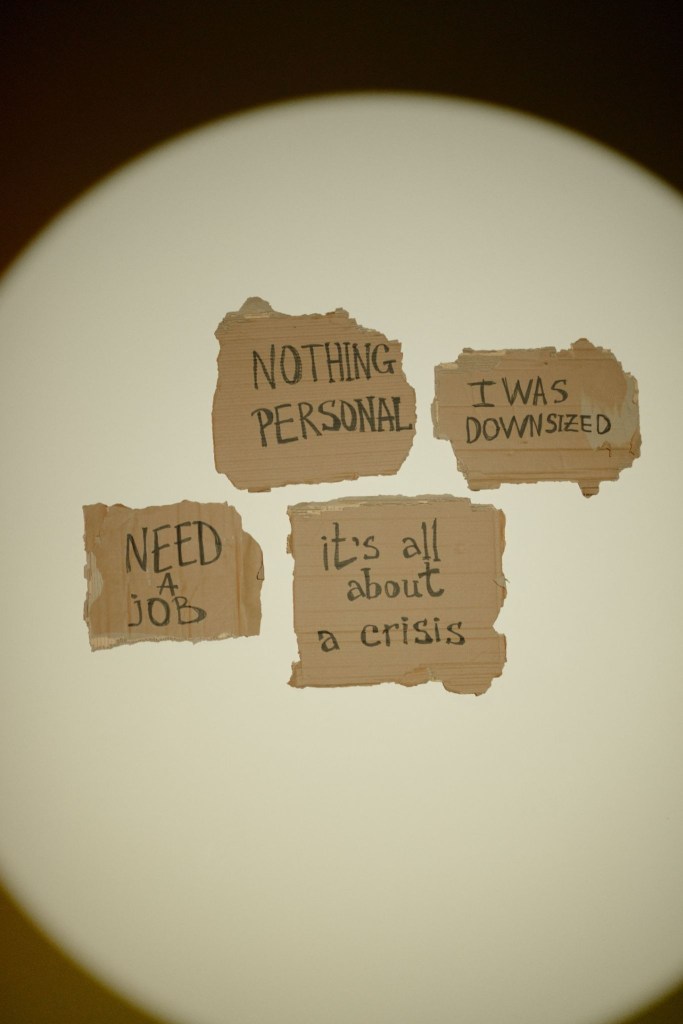 Scraps of carboard with various phrases written on them such as "Nothing personal" and "I was downsized"