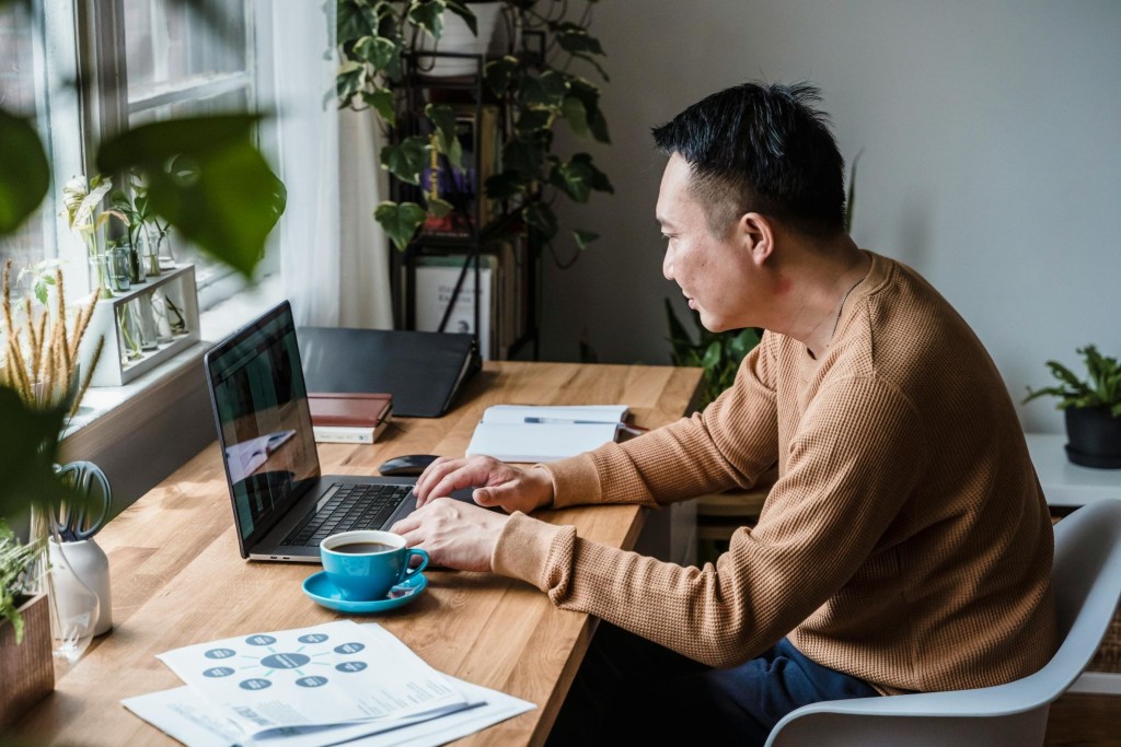 A male freelance worker sitting at his home office, typing on his laptop