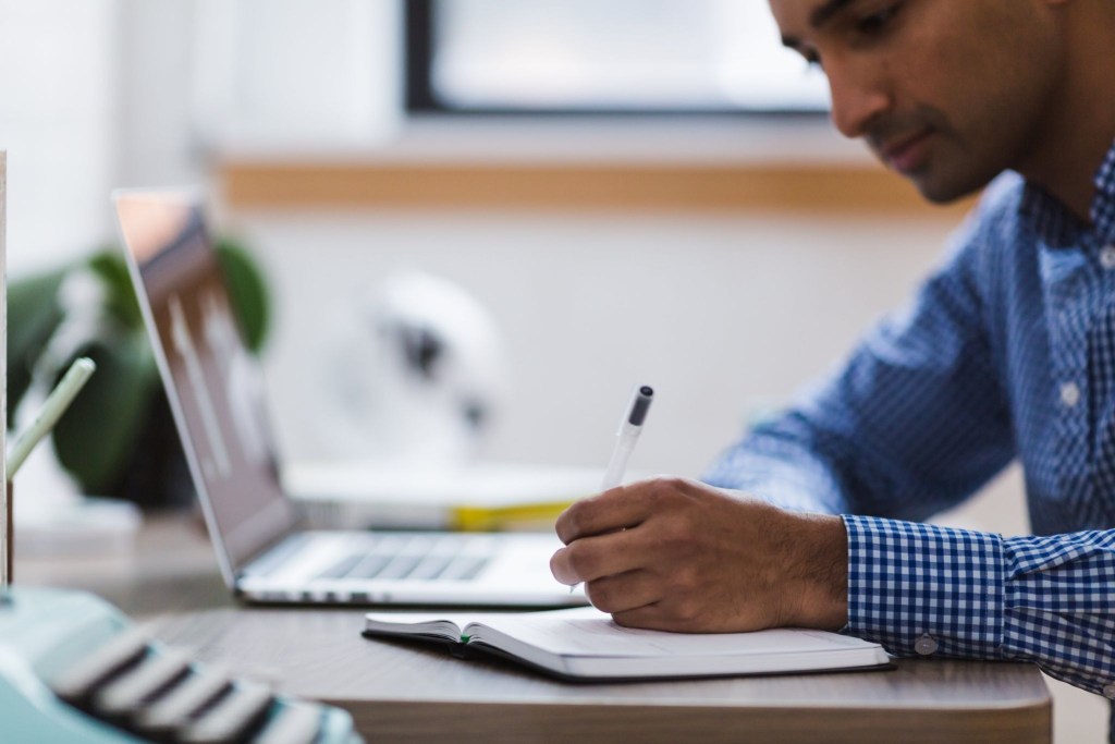 A slightly out of focus shot of a freelance worker writing at his desk