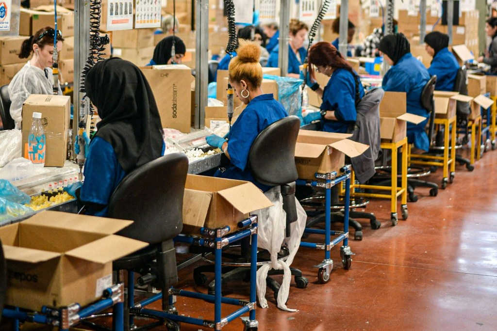 Several factory workers are sittingat their stations completing their tasks.