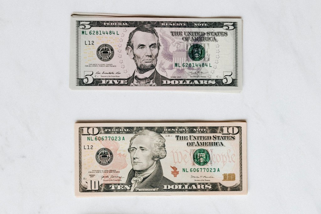 A US 5 dollar bill and and US 10 dollar bill, representing the average minimum wage for developed countries