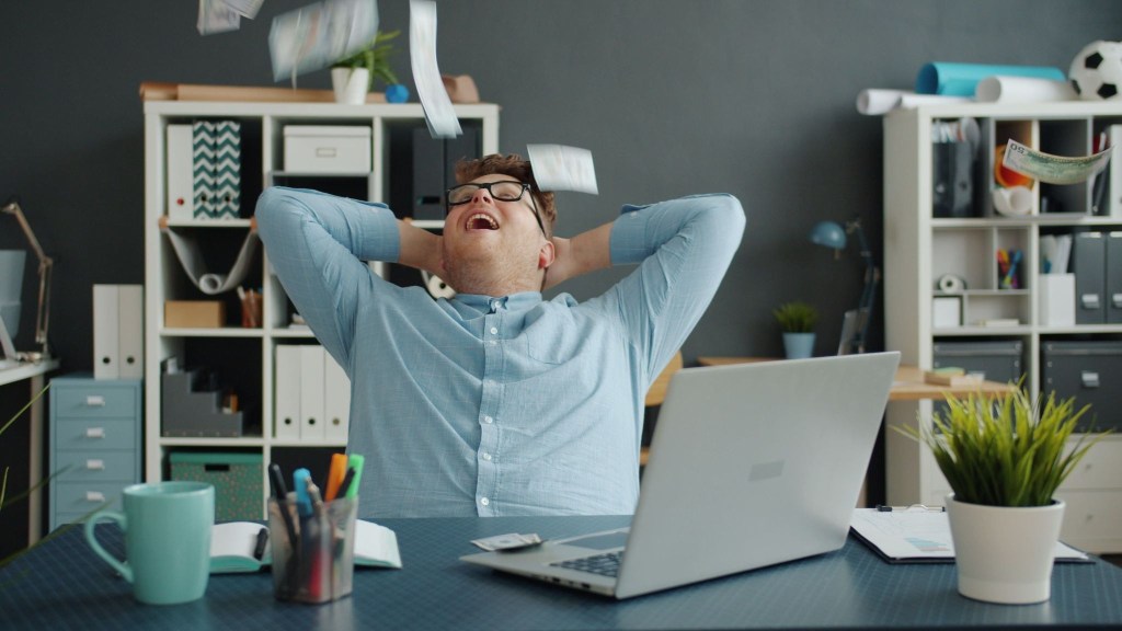 A man, leaning back in his chair, with his hands behind his head, representing landing a dream job for editors or proofreaders