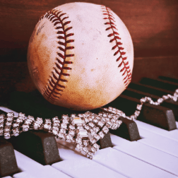 Baseball and rhinestone necklace placed on top of piano keys