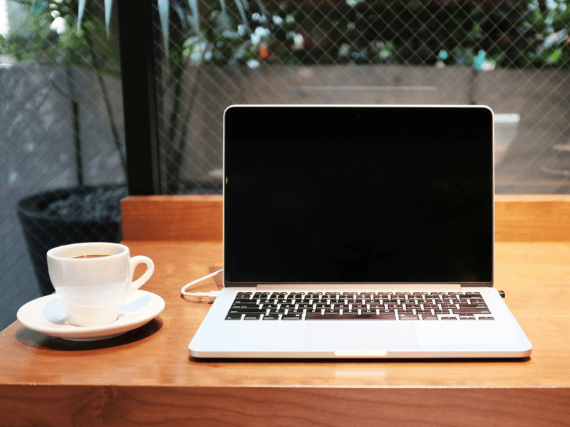 a laptop and coffee cup sit on top of a desk