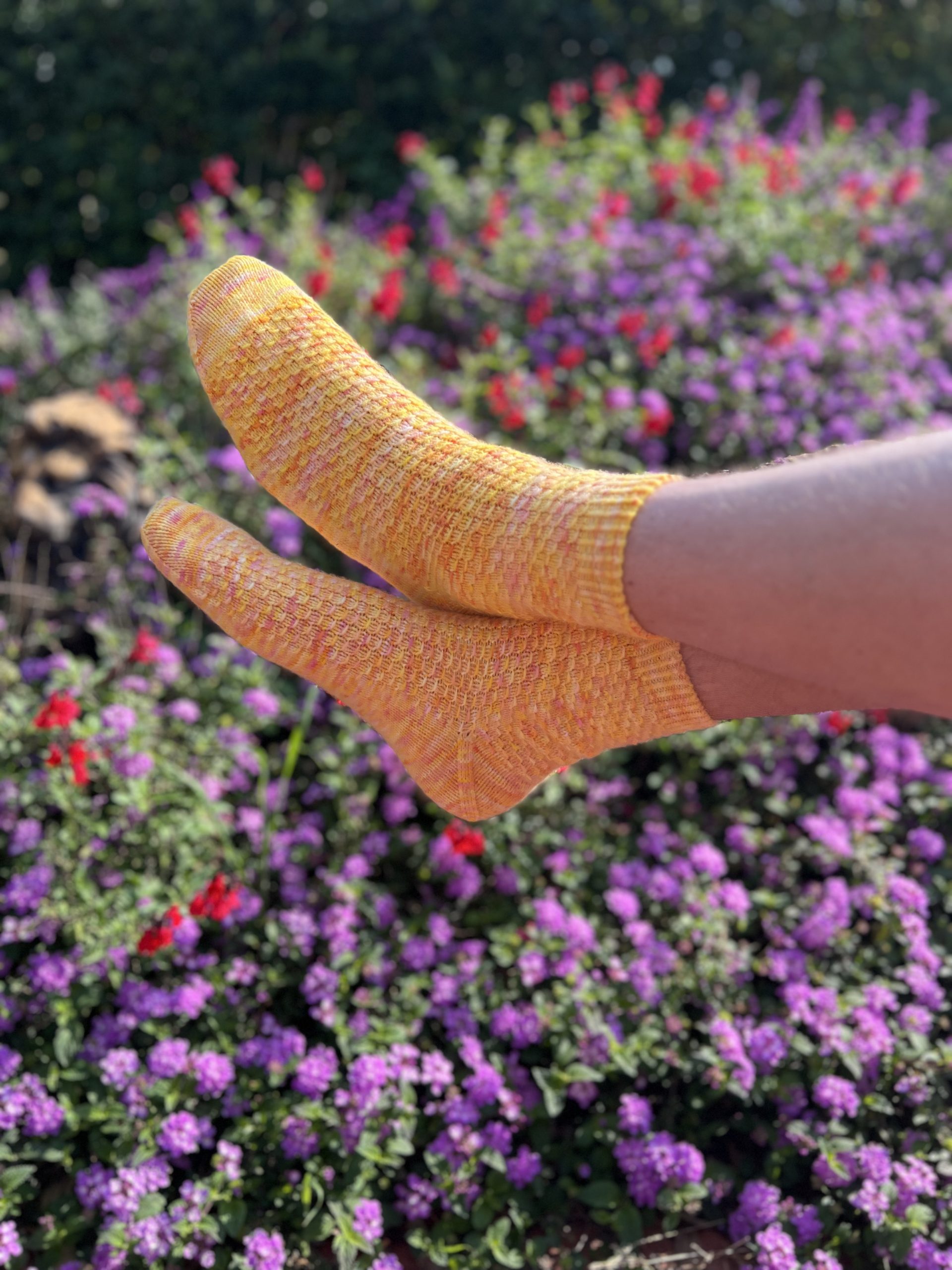 feet in yellow socks in front of flowers