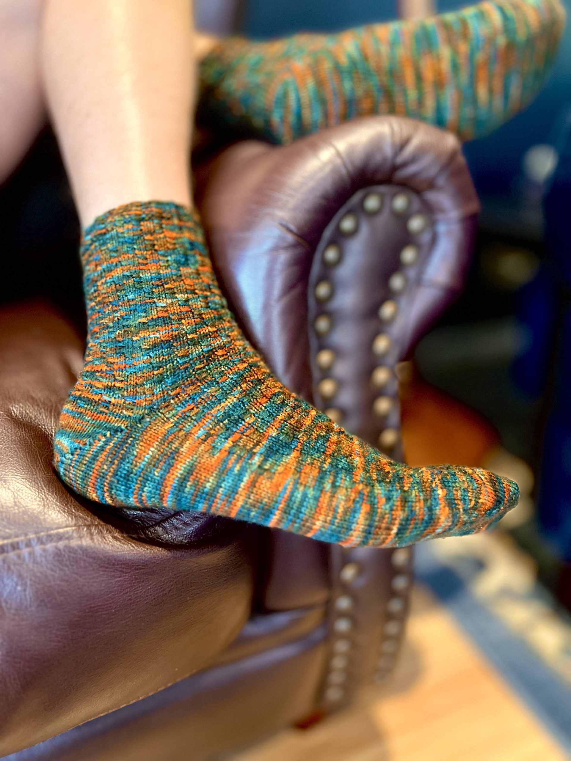 men's feet resting on the arm of a chair wearing socks