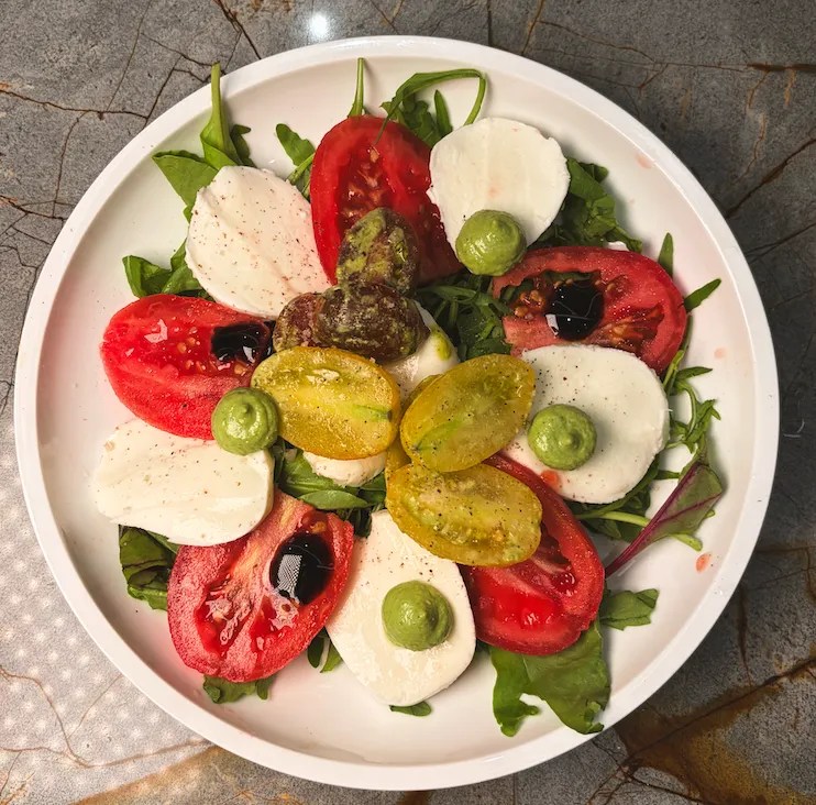 Caprese salad on a white plate served at Altito restaurant.