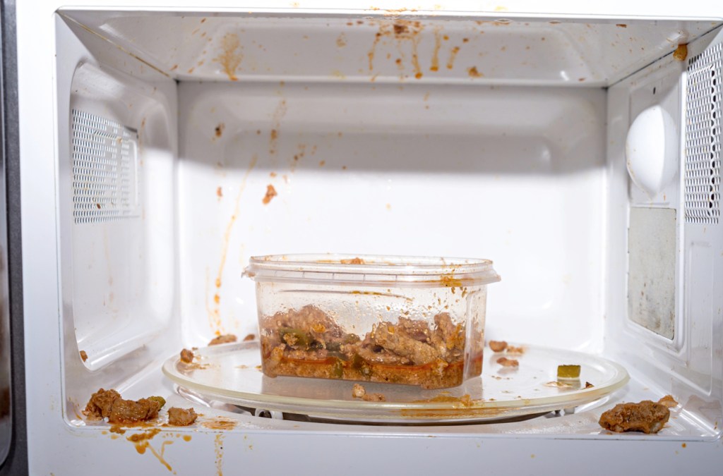 dirty microwave with a bowl of pasta inside