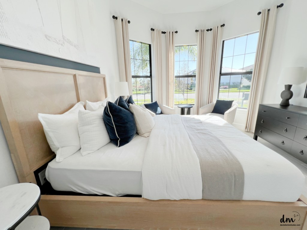 a bedroom that is neat and organized with sitting chairs near to a window