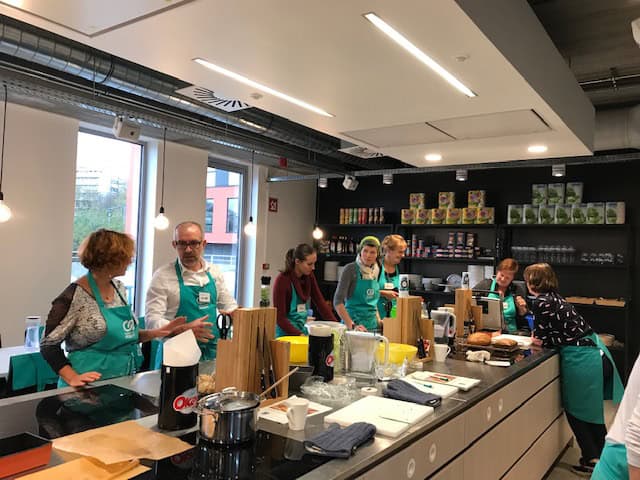 Participants réunis autour d’un plan de travail lors d’un atelier de cuisine.