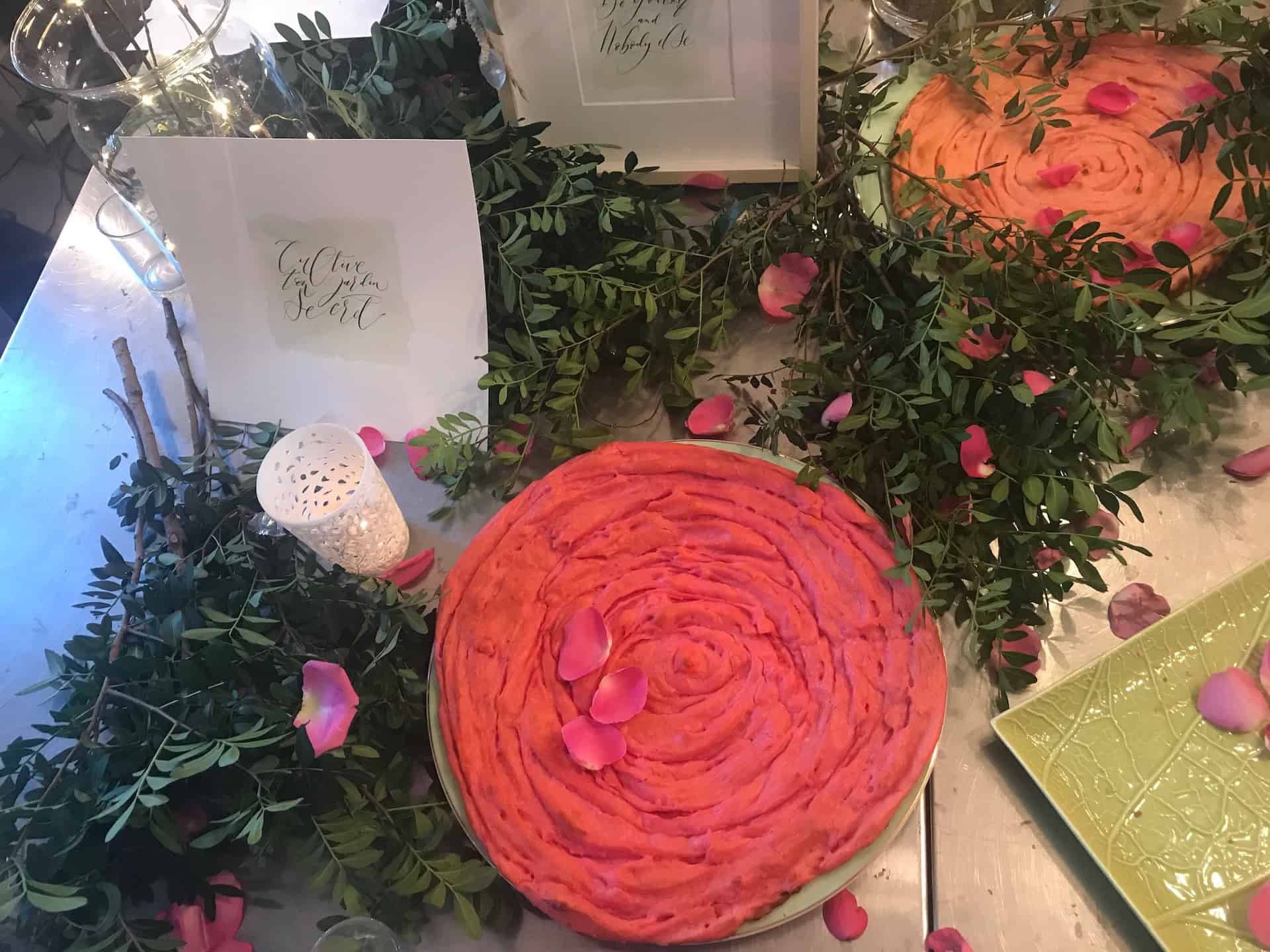 Pâtisserie ronde rose disposée sur une table décorée de fleurs.