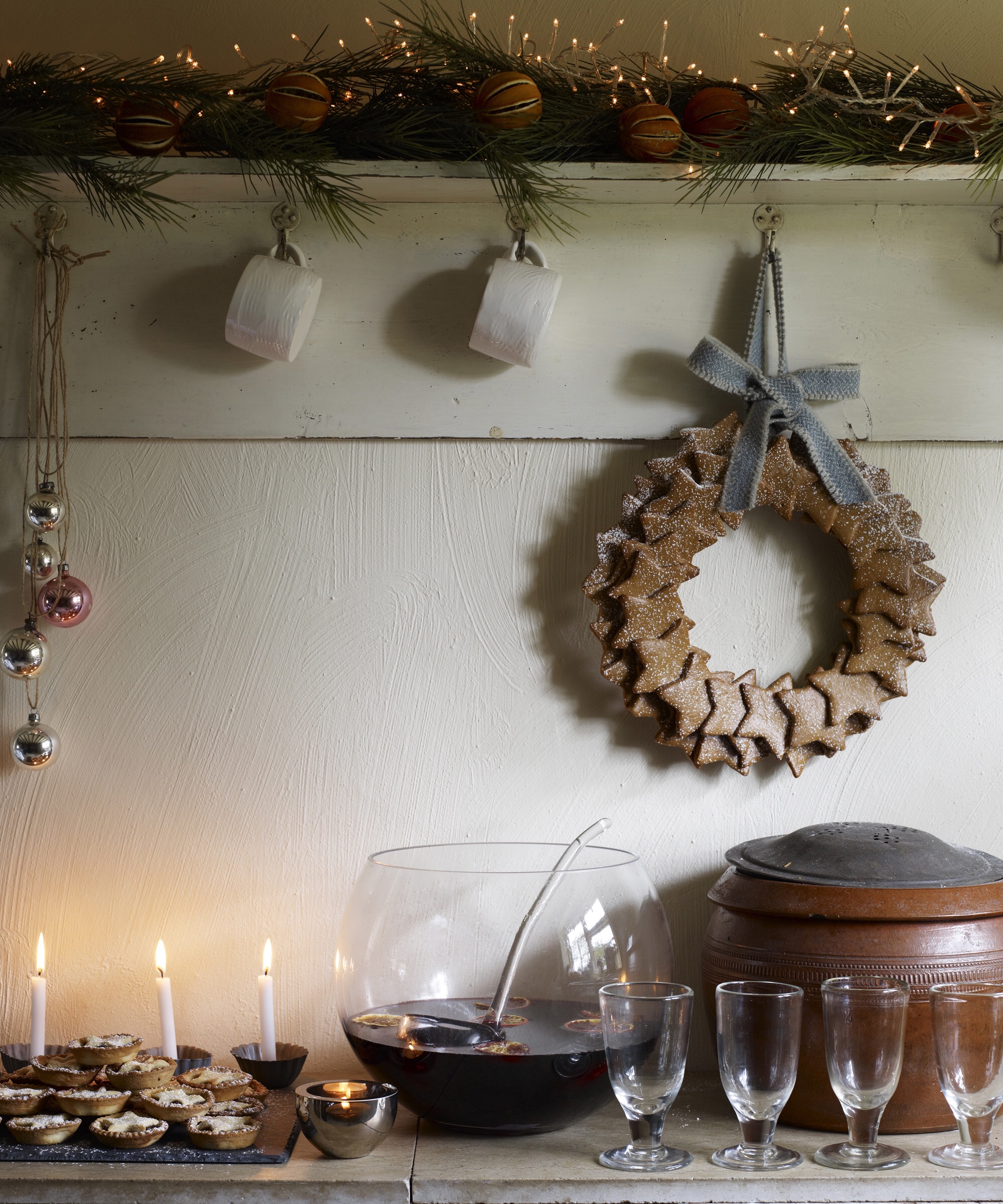 Kitchen with a festive gingerbread wreath decoration, mince pies, punch bowl of mulled wine, glasses tealight, lit candles, vintage baubles pine garland H&G 12/2010 pub orig