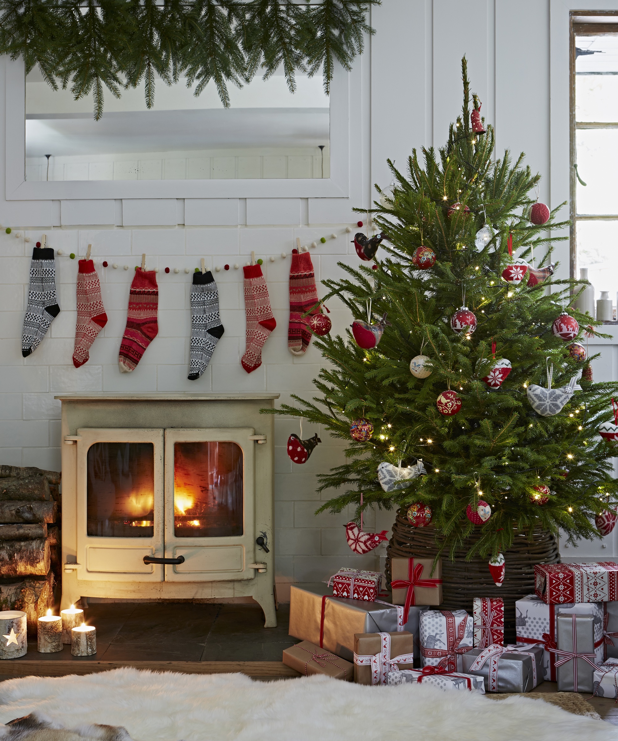 White wood panelled living room, Christmas tree with presents, lit vintage wood burning stove, socks as Christmas stockings, white blanket throw CH&I 12/2013 pub orig