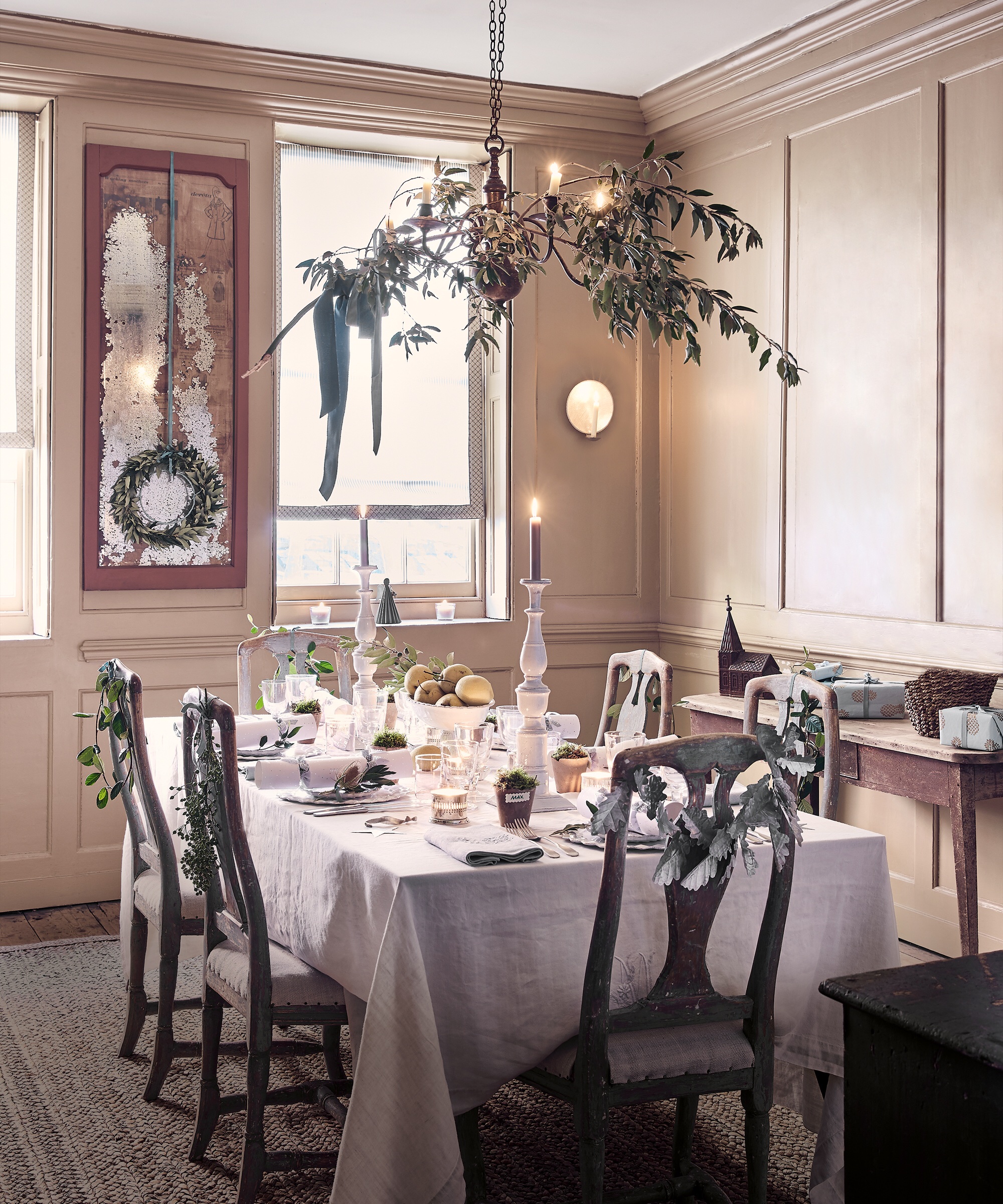 Dining room with wood panelled walls and table laid for a meal with foliage decorations on the chairs.