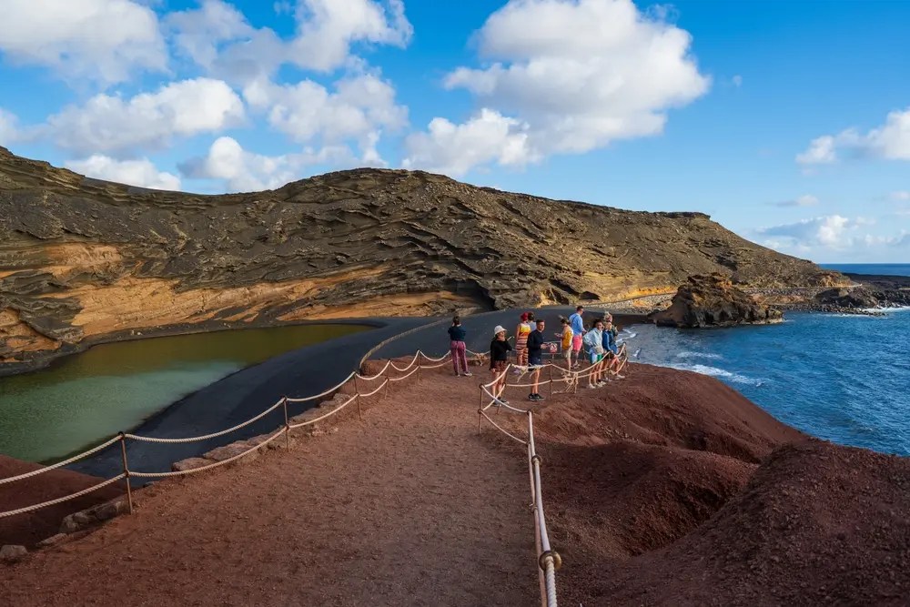 Grupo de personas observando el paisaje volcánico y la laguna verde en El Golfo, Lanzarote.