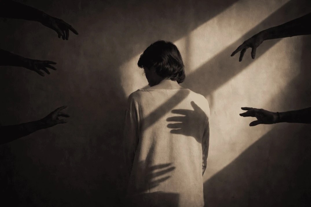 Person surrounded by reaching hands representing nervous system disregulation and burnout overwhelm
