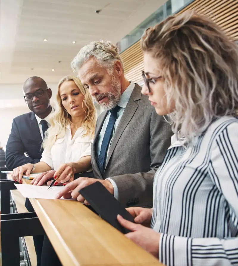 Business men and women standing in an office and working together.