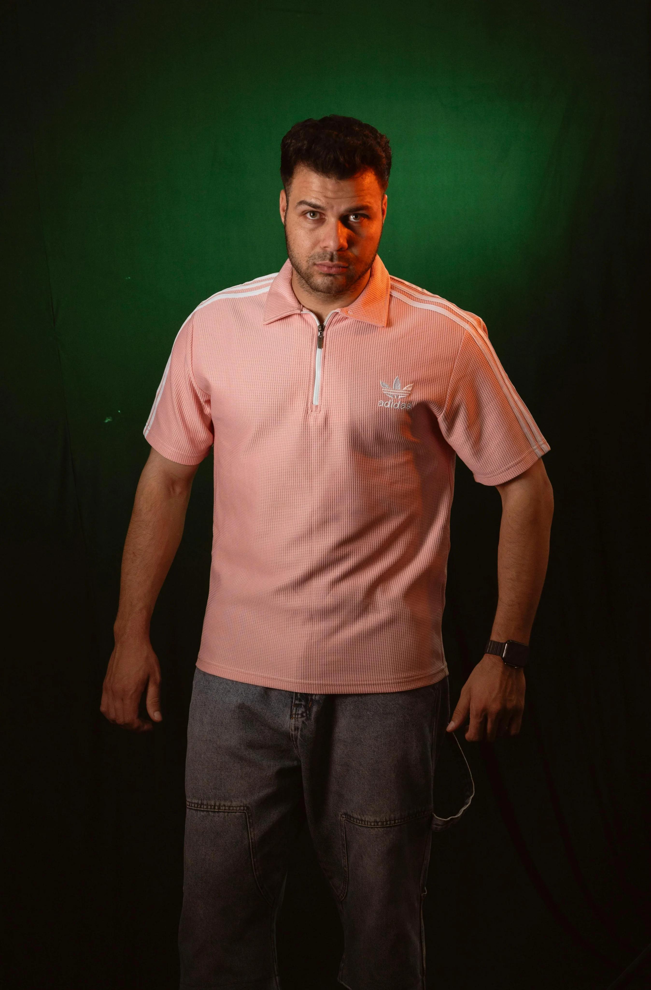 Casual look featuring a man in a pink polo shirt against a green backdrop.