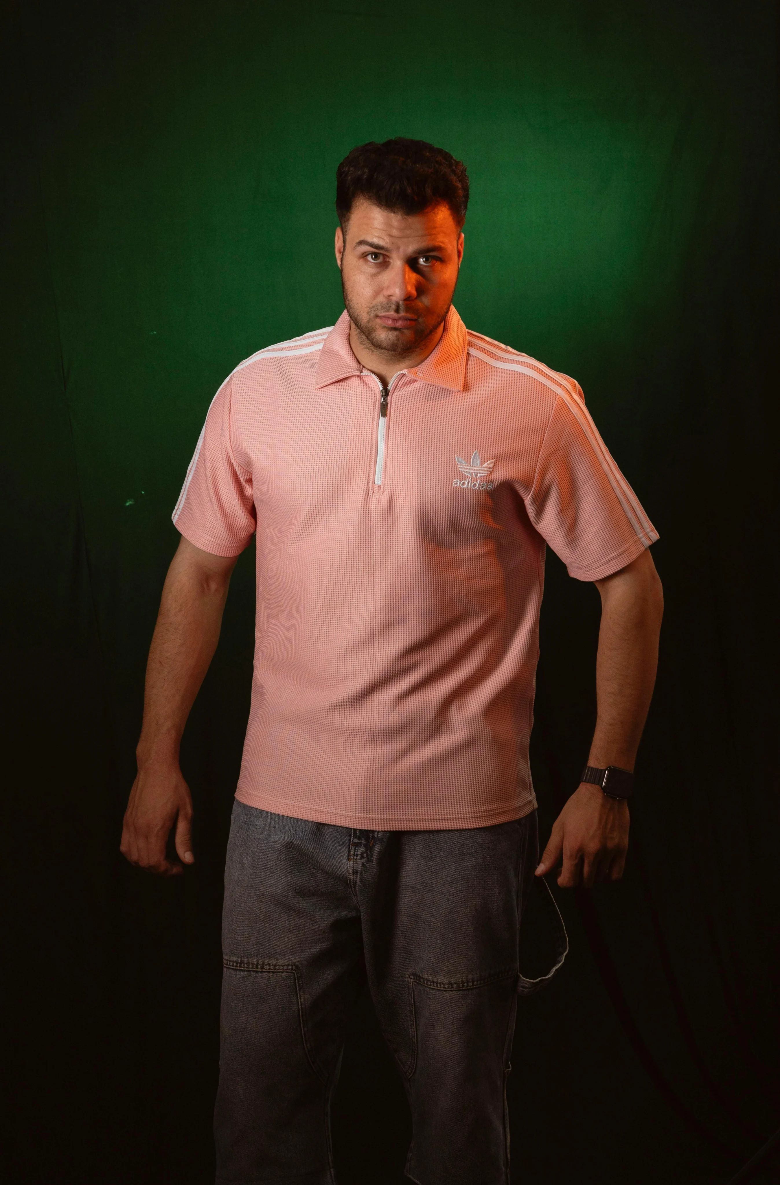 Casual look featuring a man in a pink polo shirt against a green backdrop.