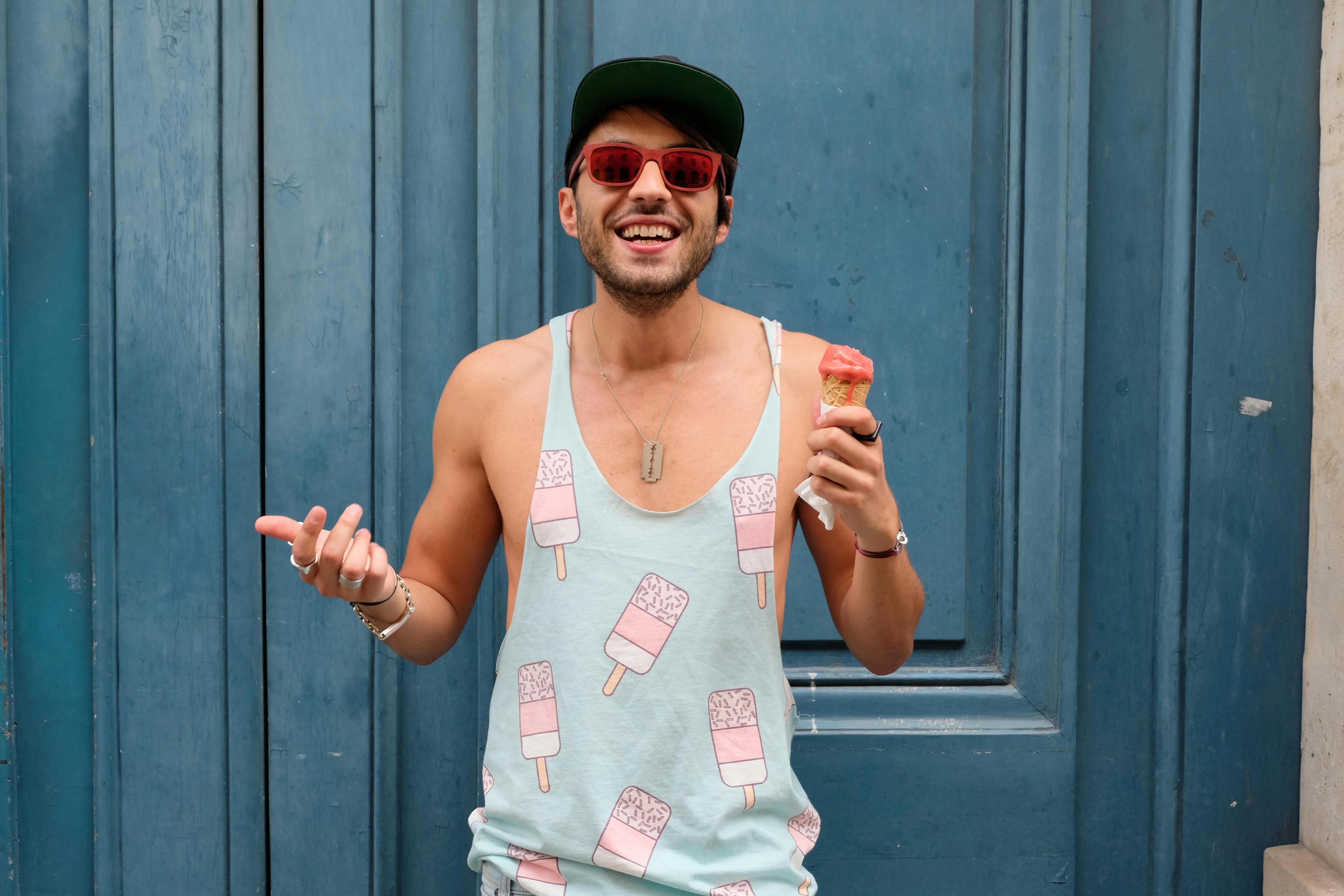 Cheerful man in a casual tank top enjoying ice cream in front of a vibrant blue door