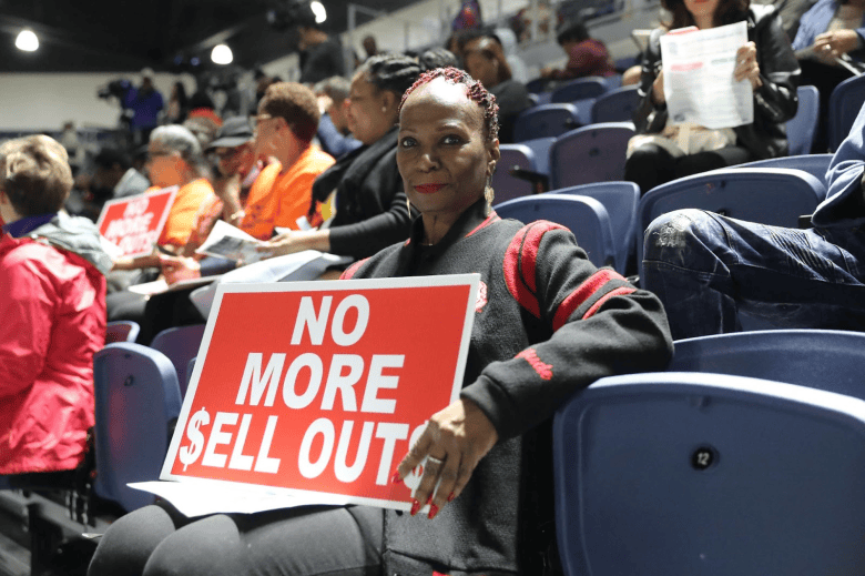 A Houston woman holds a protest sign during TEA community forum at Delmar Stadium. 
