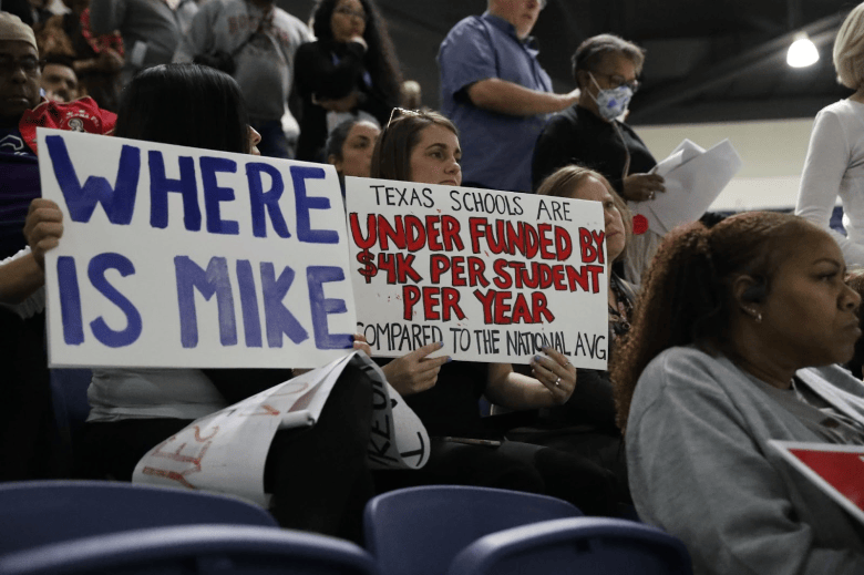 Houston residents hold protest signs during TEA community forum at Delmar Stadium