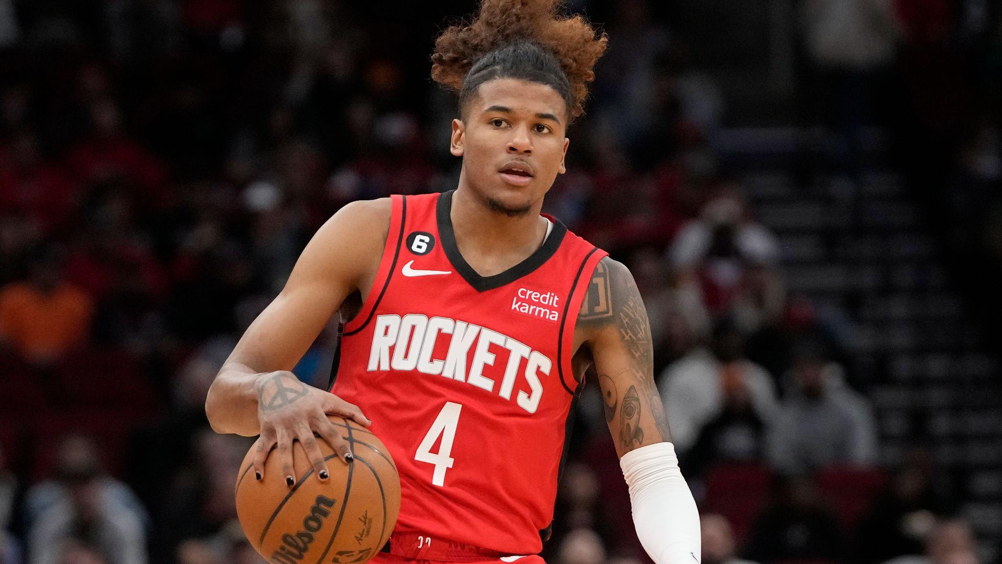 Jalen Green wearing a red Houston Rockets jersey dribbles ball on the court during a game