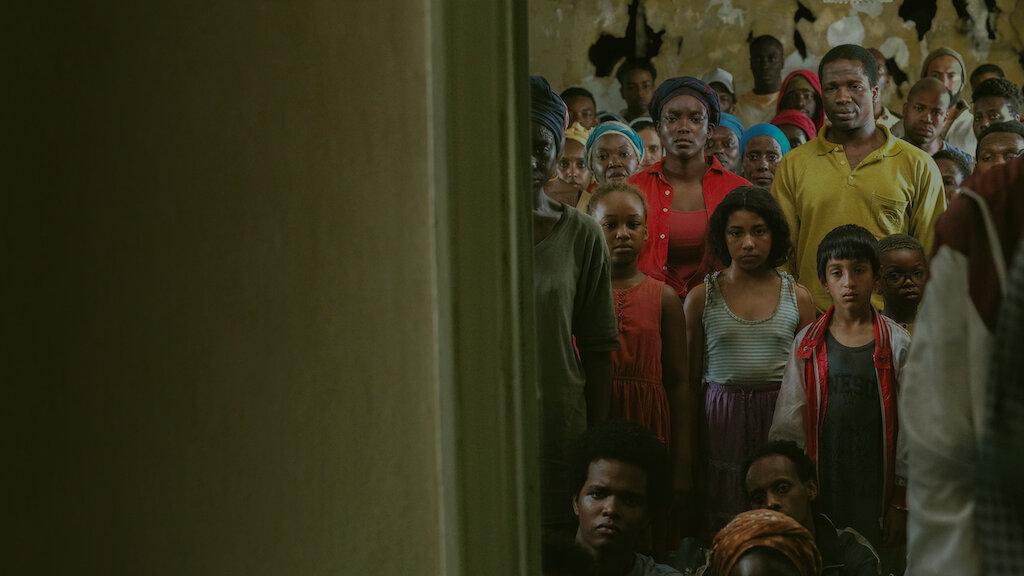 A diverse group of people of Black people standing in the doorway in a scene from "His House"