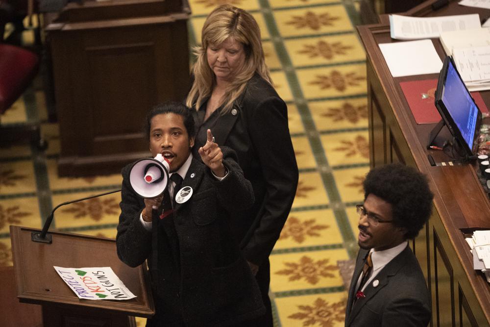 Tennessee State Representative Justin Jones speaks on a bullhorn as he stands on the congressional floor, flanked by Rep. Gloria Johnson, D-Knoxville (left), and former Rep. Justin Pearson, D-Memphis