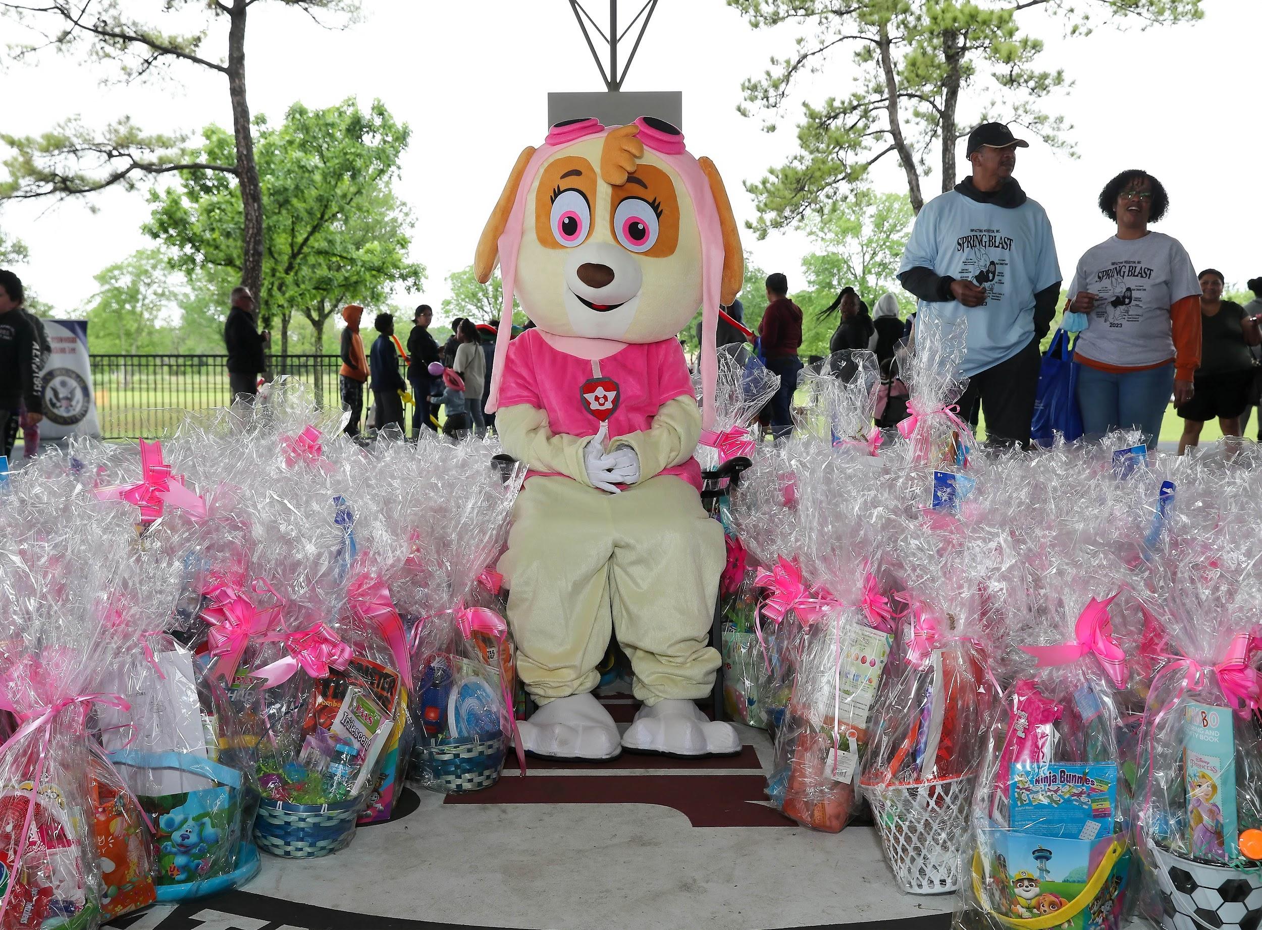 Easter Bunny mascot is seated outdoors while it's surrounded by prepared Easter baskets