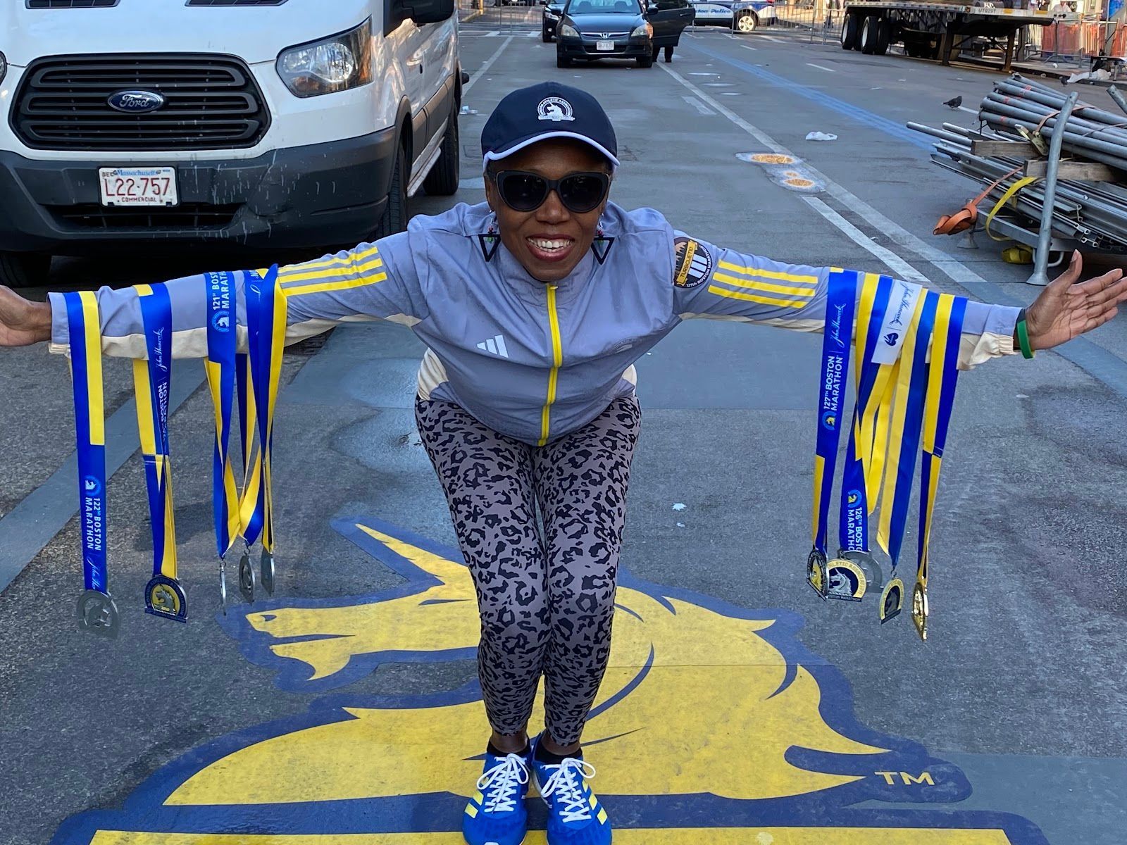 Portrait of Jetola Blair standing in the street with her medals draped over each of her arms