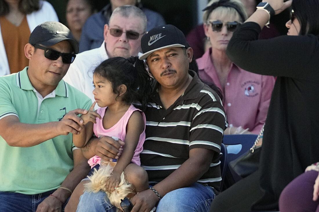 Mass shooting survivor Wilson Garcia, center, holds a young girl during a vigil for his son Daniel Enrique Laso, 9