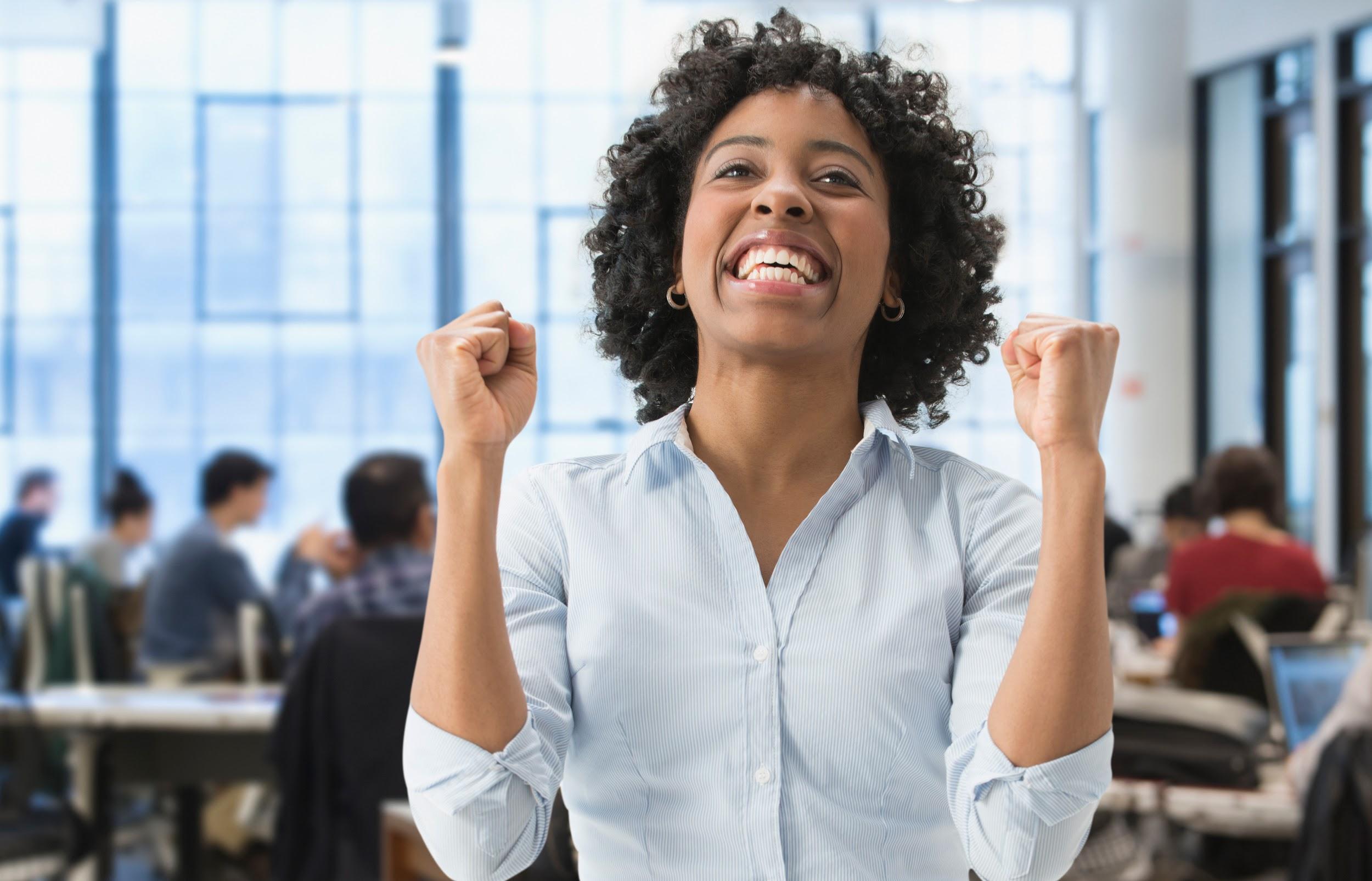 African American businesswoman cheering in office