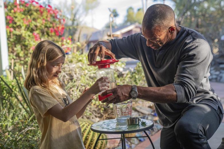 This image released by National Geographic shows Annabelle, left, and Christian Cooper making sugar water for the Costa Hummingbird feeders