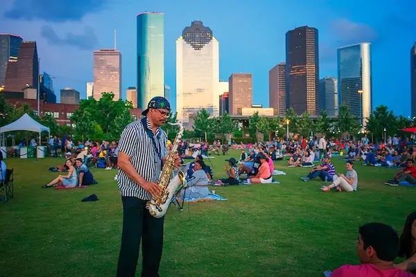 A man playing a saxophone at a park in Houston.